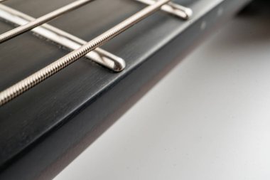 İyi işlenmiş bir gitar fretboard 'unun yakın plan görüntüsü, cilalanmış metal perdeleri ve toprak tonlarda vücudun ahşabını gösteriyor.