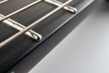 Bir gitar başlığının yakın plan fotoğrafı, metal ayar çivileri ve gergin dizgilere odaklanmayı vurguluyor. Arka plan yumuşak bulanık, dokuyu ve potansiyel pazarlama için işçiliği vurguluyor.