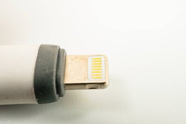 Beyaz, sıkıştırılmış Apple USB güç adaptörünün görüntüsü, gösterişli tasarımı ve çeşitli Apple cihazlarıyla uyumluluğunu gösteriyor dayanıklılık, kalite ve kullanıcı dostu deneyimi vurguluyor