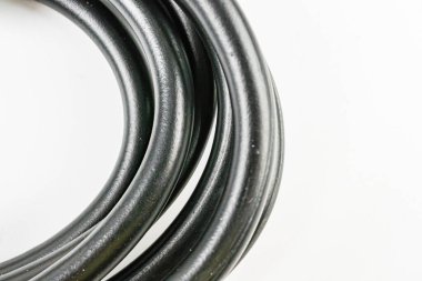 Bir rulo veya makarayı andıran siyah sarmalanmış kablo paketi görüntüsü Yeni, pürüzsüz doku muhtemelen güvenilir ve dayanıklı kabloların pazarlama bağlamında plastik odaklı ürün fotoğrafçılığı