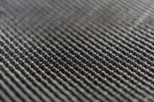 Yakın plan bir fotoğraf, karbon fiberin karmaşık çapraz modelini ortaya çıkarır, gücünü ve zarafetini gösterir, uzay, otomotiv, spor ekipmanları veya üst düzey fa pazarlama malzemeleri için idealdir