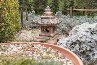 Huzur bahçesi, taş fener karanlık, doğu tarzı, kaya koleksiyonu toprak tonları, ahşap yapı, yemyeşil yol, çakıl yolu, keşif teması, fener ve kayalara odaklan, metin veya insan yok,