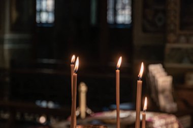 Filtrelenmiş doğal ışığın altında simetrik olarak dizilmiş yedi mumla kilise sığınağı. Vitray pencerelerden geçerek. Eski geleneksel mimari.
