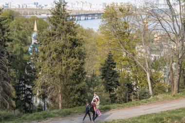 Şehir zeminindeki bir nehre giden sakin bir açık hava sahnesi, yayalar ya da yürüyüşçülerle dolu yoğun bitki örtüsü, sıcak bitki örtüsü Kyiv, Ukrayna 04-19-2025