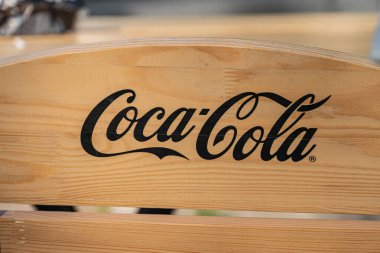 Tahta bank, Coca-Cola logosu, açık hava ayarı, doğal ışıklandırma, ahşap tonlar, zıt renkler Kyiv, Ukrayna 04-19-2025