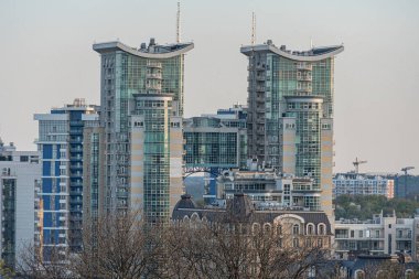 Gündoğumunda ya da batımında modern şehir manzarası yansıtıcı cam cepheli ve eğimli tasarımlı yüksek binalar sonbaharın sonlarında, kışın sonlarında ya da erken saatlerinde Kyiv, Ukrayna 04-19-2025