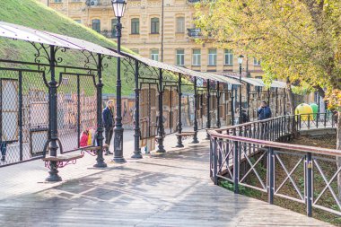 Bireysel duruş, kapalı alan, lamba direği, yayalar, ağaç, tarihi bölge, doğal ışıklandırma, gizli fotoğraf, sonbahar yaprakları, öğle vakti veya Kyiv, Ukrayna 10-11-2024