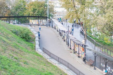 Şafakta ya da alacakaranlıkta şehir manzarası, kır evleri, yemyeşil yamaçlar, yayalar, sıradan atmosfer, antika tarihi binalar, yumuşak ışık, ılık tonlar, Europea Kyiv, Ukrayna 10-11-2024