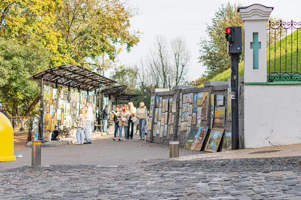 Sokak sahnesi kaldırım taşları, eski dünya cazibesi, kilise benzeri bina, açık tezgah, renkli posterler, sarı şemsiye tahtası, sonbahar ağaçları, yumuşak li Kyiv, Ukrayna 10-11-2024