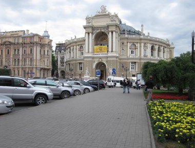Şafak vakti Avrupa şehir manzarası, yemyeşil bitkiler, kaldırım, kaldırım taşı caddesi, büyük tarihi bina, klasik mimari, balkonlar, heykeller, yayalar, c-Odessa, Ukrayna 06-07-2012.