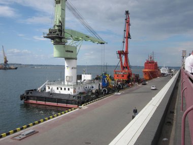 Liman sahnesinde yeşil bir sanayi vinci, iki kırmızı römorkör ve birçok gemi rıhtıma yanaştı. Büyük beyaz bir gemi, görünür, sakin su, pa Odessa, Ukrayna 06-07-2012