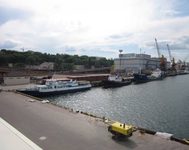 Çeşitli teknelerin eğlence amaçlı olduğu liman sahnesi, durgun sularda ticaret, parçalı bulutlu gökyüzü, endüstriyel gemiler, kargo bölmeleri, grimsi su, sabah geç saatlerde Odessa, Ukrayna 06-07-2012.
