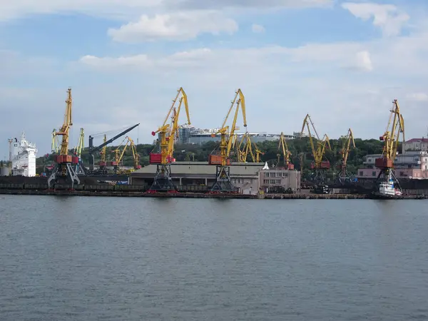 Gündüz vakti çoklu kargo vinçleri, sarı, kırmızı, bir tekne ve büyük gemi çok katlı, metal gövde, pencereler, sakin su ışığı Odessa, Ukrayna 06-07-2012