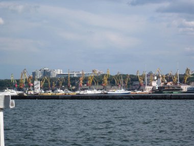 Aktif liman, beton iskele, endüstriyel ekipman, büyük sarı vinçler, küçük tekneler römorkörler, feribotlar, balıkçı tekneleri, büyük gemi - Odessa, Ukrayna 06-07-2012.