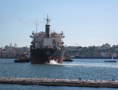 Kırmızı ve beyaz işaretli kargo gemisi sakin limanı terk ediyor, vinçler görünürde demirlemiş veya taşlardan yapılmış uzak gemiler Odessa, Ukrayna 06-07-2012.