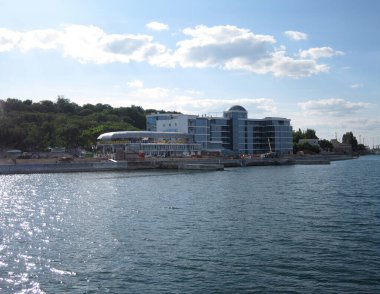 Sakin bir göl veya körfez üzerinde modern, eğri çatılı bir binanın yer aldığı sakin bir rıhtım sahnesi mimari, Odessa, Ukrayna 06-07-2012 geçici oturma düzenine sahip bir etkinlik alanını akla getiriyor..