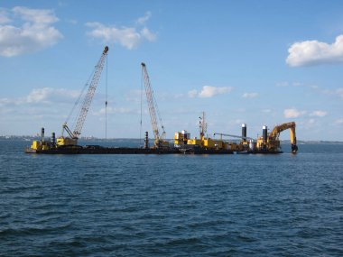 Endüstriyel vinç mavnası genişletilmiş, kısmen durgun suya batırılmış. Soldaki sarı platform veya şamandıra, muhtemelen devam eden inşaat operasyonu Odessa, Ukrayna 06-07-2012 ile ilgili.