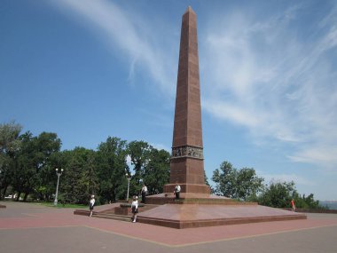 Obelisk koyu kahverengisi yemyeşil ve uzun ağaçlarla çevrili Kırmızı plaza halkı çevreyi düşünüyor ya da eğleniyor Nat Odessa, Ukrayna 06-15-2012