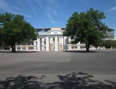 Kentsel bir ortamda neoklasik mimari, gün ışığı, sütunlar ve pedikürlü simetrik cepheler, merkezi giriş, heykeller, açık asfaltlı alan avlusu veya karesi - Odessa, Ukrayna 06-15-2012.