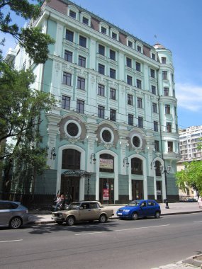 Açık yeşil, çok katlı, kemerli pencereli ve dairesel pencereli sokak manzarası kaldırım araçlarındaki iki yaya Odessa, Ukrayna, 06-15-2012