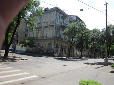 Modern-klasik mimarisi olan, küçük beton bir avlu ve yemyeşil ağaçların önünde duran üç katlı sakin bir sokak manzarası Odessa, Ukrayna 06-15-2012