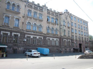 Birden fazla katlı, büyük pencereli ve tarihi bir şehirde park yeri olan eski tarz bir bina mavi bir van Doğal Odessa, Ukrayna 06-15-2012 de dahil olmak üzere birçok araba park edilmiştir.