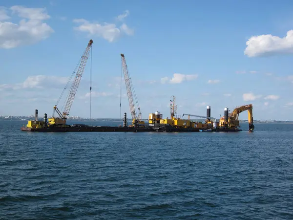 Endüstriyel vinç mavnası genişletilmiş, kısmen durgun suya batırılmış. Soldaki sarı platform veya şamandıra, muhtemelen devam eden inşaat operasyonu Odessa, Ukrayna 06-07-2012 ile ilgili.