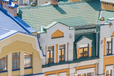 Çok katlı, tarihi binalar, yeşil, mavi ve sarı cepheli, çatılarda süslü fayanslar ve desenlerle süslenmiş her binanın koyu renk ahşap pencere çerçeveleri var.