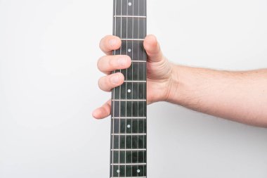 Tahta bir gitar fretboard 'unun üzerinde yakın plan bir el, köprünün yakınındaki tellere basma Tahta ve metal teller, nötr arka plan