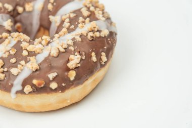Yuvarlak çikolatalı vanilyalı donut. Hafif bir yüzeyde doğranmış fındıklı, yukarıdan hafif ışıklandırmalı.