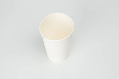 Merkezi, düz yüzey üzerinde sarımsı sıvıyla servis edilen strafor bardak yukarıdan gelen ışık kaynağı yumuşak gölgeler yaratır ve iç parıltı tanımlanamayan arka plan bardağa odaklanır