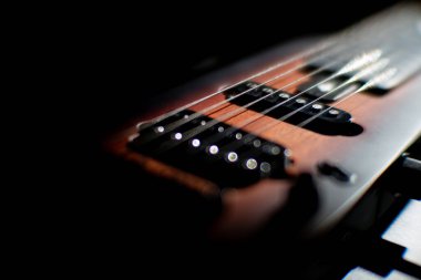 Koyu telli açık kahverengi elektro gitarın yakın çekimi, koyu fretboard ve gümüş perdelerin yumuşak gölgesi yukarıdan veya önden gerçekçi tarzda, sicimler ve perdelere keskin bir odaklanma önerir.