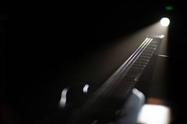 Koyu renk elektro gitar yaka, kuyrukta frets, başlık görünür, düşük ışık ayarı, dikey oryantasyon, uzun gölgeler, doku ve tahıl görünür