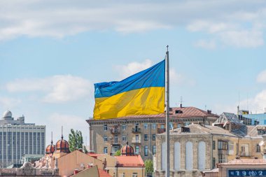 Ukrayna ulusal bayrağı sallanıyor. Bulanık binaları olan güzel bir direk. Bağımsızlık Günü için Ukrayna ulusal bayrağı.