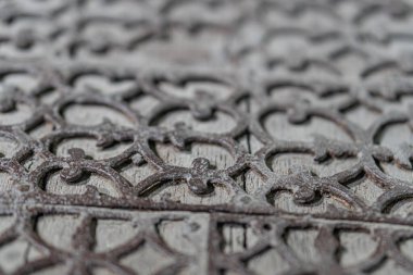 Yıpranmış, desenli, geometrik desenli, muhtemelen bir ızgara içinde kareler ve daireler içeren paslanma ve aşınma nedeniyle aşınmış bir metal yüzeyin yakın görüntüsü, resim loş bir şekilde ışıklandırılmış ve vurgulanmıştır.