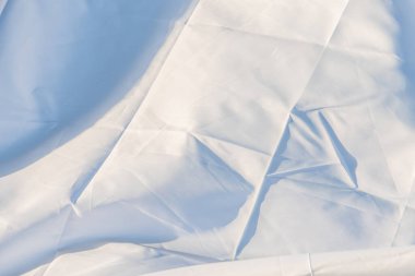 İnce gölgelendirmeli, karmaşık dokumasına ve dokusuna odaklanan, katlanmış beyaz bir tekstilin yakın plan görüntüsü.