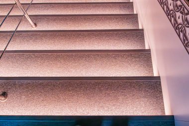 Beton ya da birleşik, desenli kaplamalı modern merdiven, Derinlik 'ten sıcak bir ışıltı ve yükseliş, daha koyu bir alana doğru, gerçekçi bir fotoğrafçılık tarzına işaret ediyor.