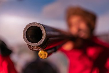 Bir insan açık havada büyük metal bir mekanizmayı çalıştırıyor. Cihazın içinden çıkan birden fazla küçük tüp var. Sığ alan derinliği hareketi vurguluyor.