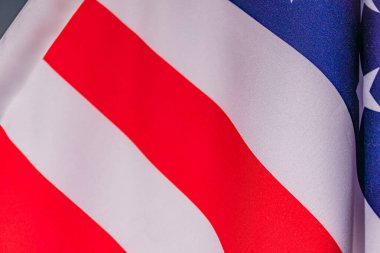 Alternatif kırmızı ve beyaz çizgili ve mavi alanlı bir Amerikan bayrağının yakın çekimi. Yıldızların tam direkte dalgalanması ya da yüksek bir yapıya bağlı olması muhtemel kırmızı renkler.