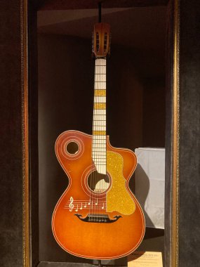 Vitrin kutusunda klasik akustik gitar, altın metal parçaları olan kahverengi gövde akor, köprü, dekoratif f delikler, nadir bulunan gitar metni, ahşap tahıl Kyiv, Ukrayna 06-19-2022