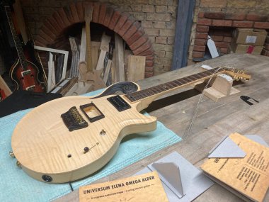 Teçhizatlar, kağıtlar ve ahşap işçiliği eşyalar arasında tamamlanmamış ahşap gitar aşınmış zemin, tuğla duvarlar ve ov Kyiv, Ukrayna 06-19-2022 'den bastırılmış ışıklandırma ile endüstri ortamında