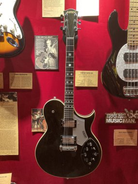 Bir müze ortamında elektro gitarların çeşitli tasarımları, siyah, beyaz, kahverengi, başlıklar yukarı, fretboardlar, görünür pikaplar, benzersiz detaylar, kırmızı sırt Kyiv, Ukrayna 06-19-2022