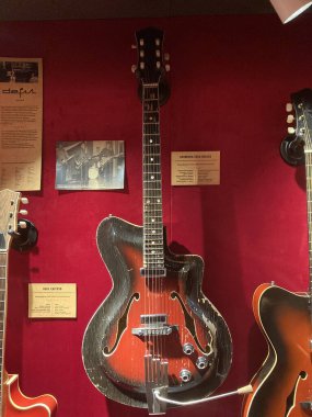 Beyaz kenarlı kırmızı kadife bir arka plana monte edilmiş klasik gitarlar, sol alt köşede sanatsal olarak düzenlenmiş küçük bir plaket, zarif müze hissi, yumuşak hafif hafif hafif Kyiv, Ukrayna 06-19-2022