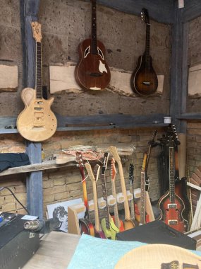Gitar üreticileri için kapalı çalışma alanı, çeşitli akustik, elektrik, tamamlanma aşamaları, dağınık ışıklandırma, ahşap raflar, tuğla duvar, Kyiv, Ukrayna 06-19-2022