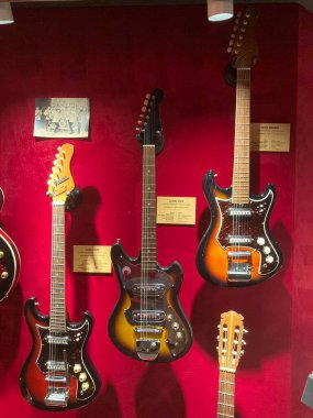 Kırmızı gradyan arka planda elektro gitar koleksiyonu, iki sıra halinde düzenlenmiştir. Bir sıra farklı renkte güneş patlaması, siyah, beyaz, hatta ışıklandırma, promosyon Kyiv, Ukrayna 06-19-2022