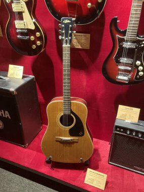 Kırmızı kadife üzerinde akustik gitar, eşsiz renk ve stillere sahip çeşitli gitarlar, müzik mağazası dekorasyonu, sıcak ortam aydınlatması, enstrüman topluluğu, hoparlör, potenti Kyiv, Ukrayna 06-19-2022