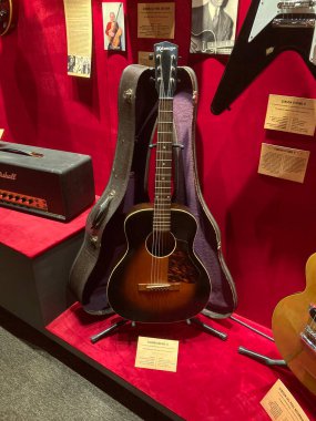 Kırmızı kadife raflarda sergilenen gitar koleksiyonu, gitar stillerinin ve tasarımların çeşitleri odak noktasında merkezi bir akustik gitarla görülebilir. Sergi Kyiv, Ukrayna 06-19-2022