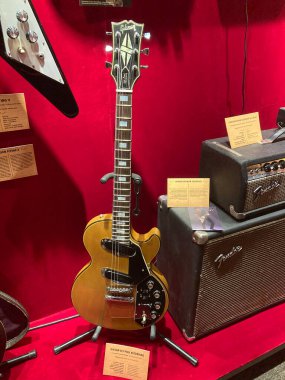 Kırmızı yüzeyde, Kyiv, Ukrayna 06-19-2022 'de sergilenen bir sergide etiketli ve amfi başlı klasik güneş patlaması elektrogitarı sergilendi.