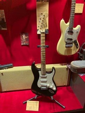 Siyah bir hoparlördeki Fender Stratocaster gitarı siyah kenarlı kırmızı arka plan, üç tek bobinli kamyonet, dört sürgülü boyunluk, ne Kyiv, Ukrayna 06-19-2022 yazılı metin kartları.