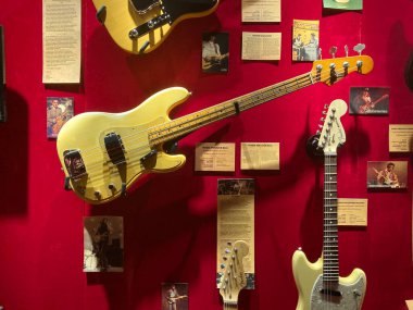 Canlı sarı bas gitarlı kırmızı fon, iki açılı elektro gitar, görünür teller, duvarda kağıt ve fotoğraflar, parlak sıcak ışıklandırma Kyiv, Ukrayna 06-19-2022